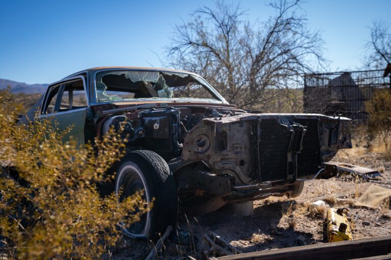 Vieille voiture abandonnée devant un bâtiment urbain.