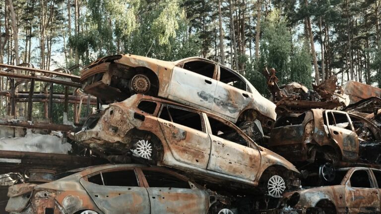 Épave de voiture brûlée abandonnée dans une forêt.