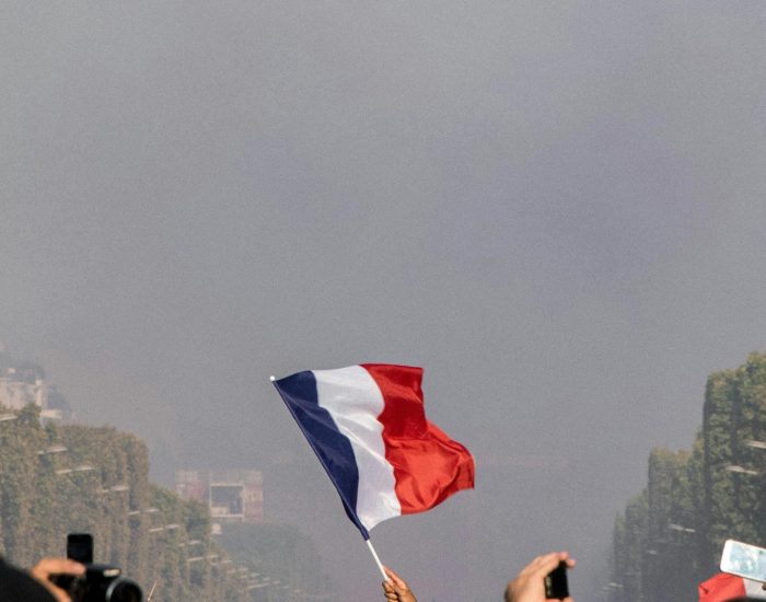 Drapeau français brandi fièrement parmi une foule, symbolisant l'esprit national et la couverture des services des Épavistes France à travers le pays.