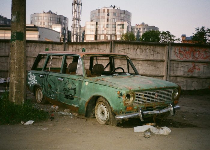 Épave d'une ancienne voiture abandonnée en milieu urbain.